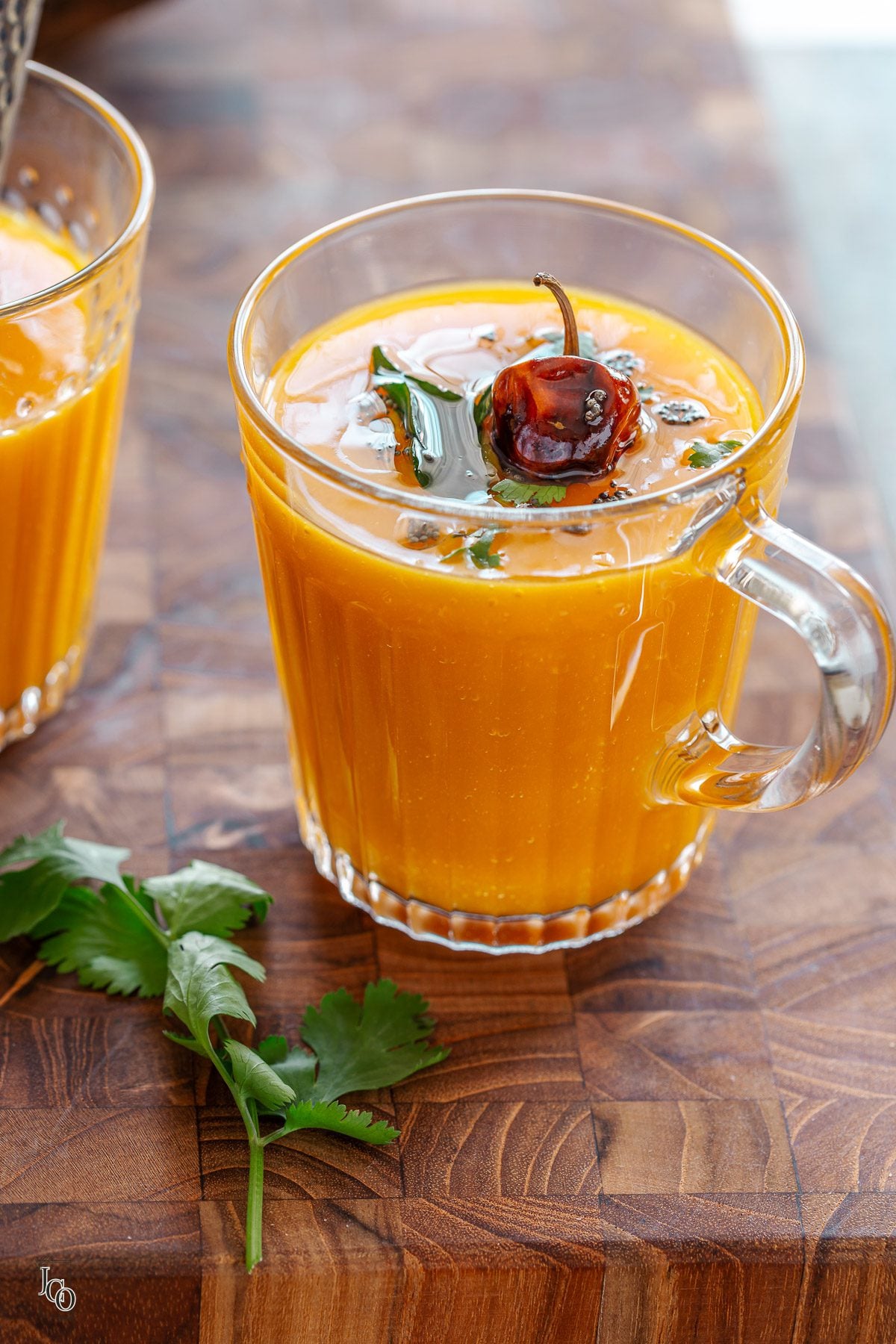 fajeto served in a glass and topped with indian tadka. Placed on a wooden chopping board.