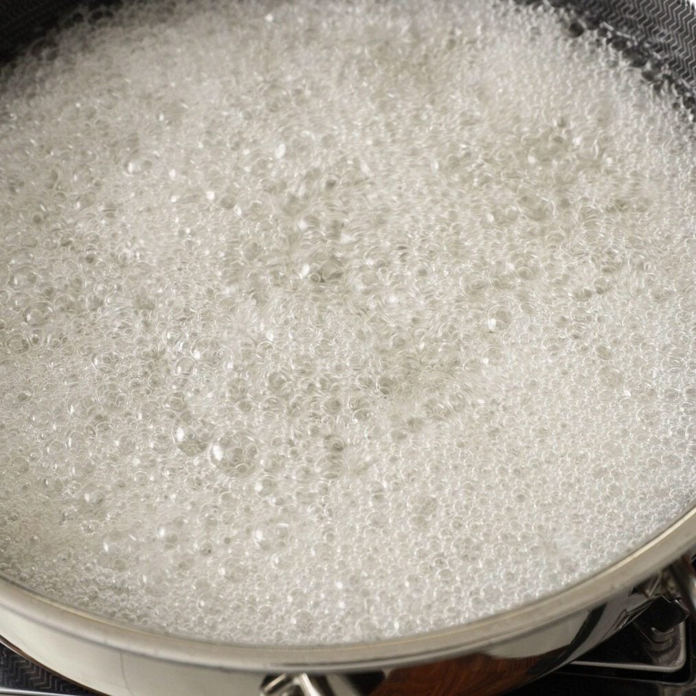 Sugar syrup boiling in a pan.