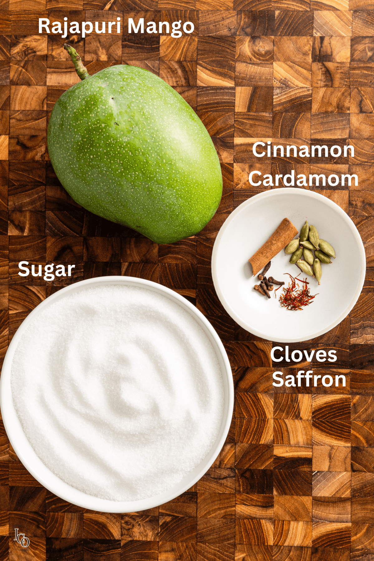 Keri murabba ingredients such as large mango, sugar and spices placed on the wooden chopping board.