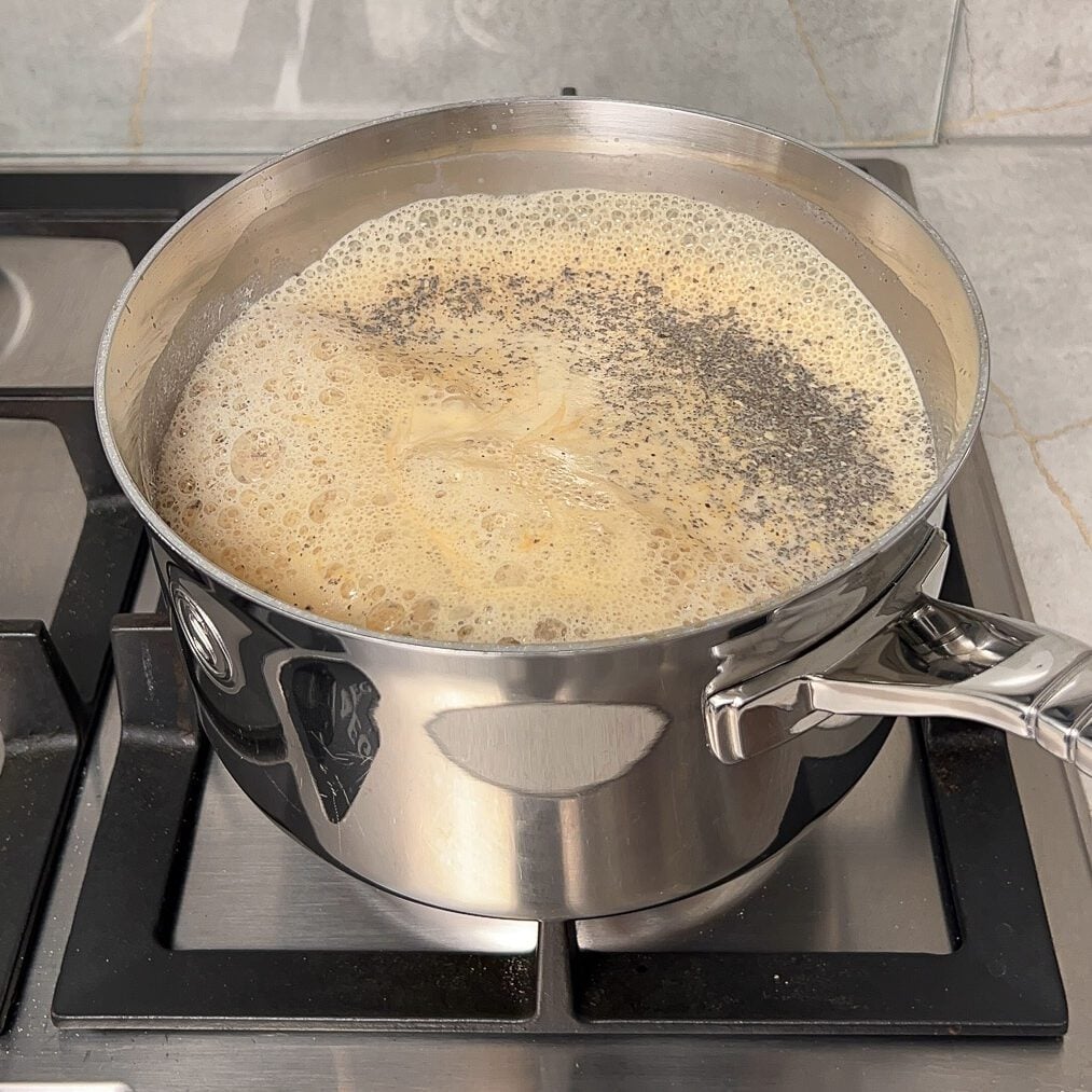 Chai is boiling in a pan over the stovetop.