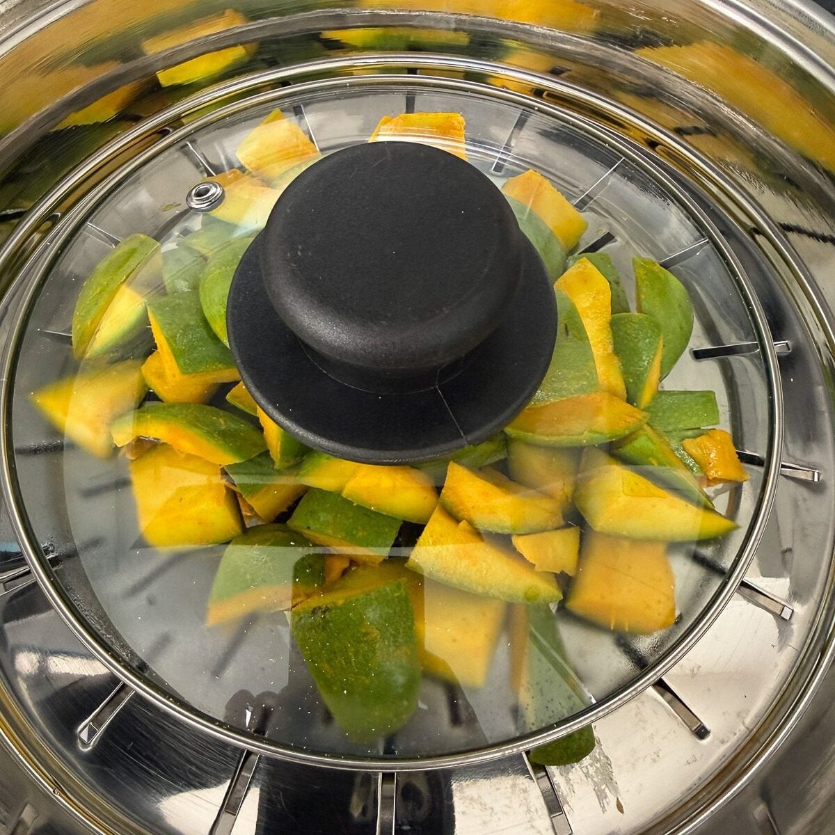 Raw mango pieces steaming on stovetop.