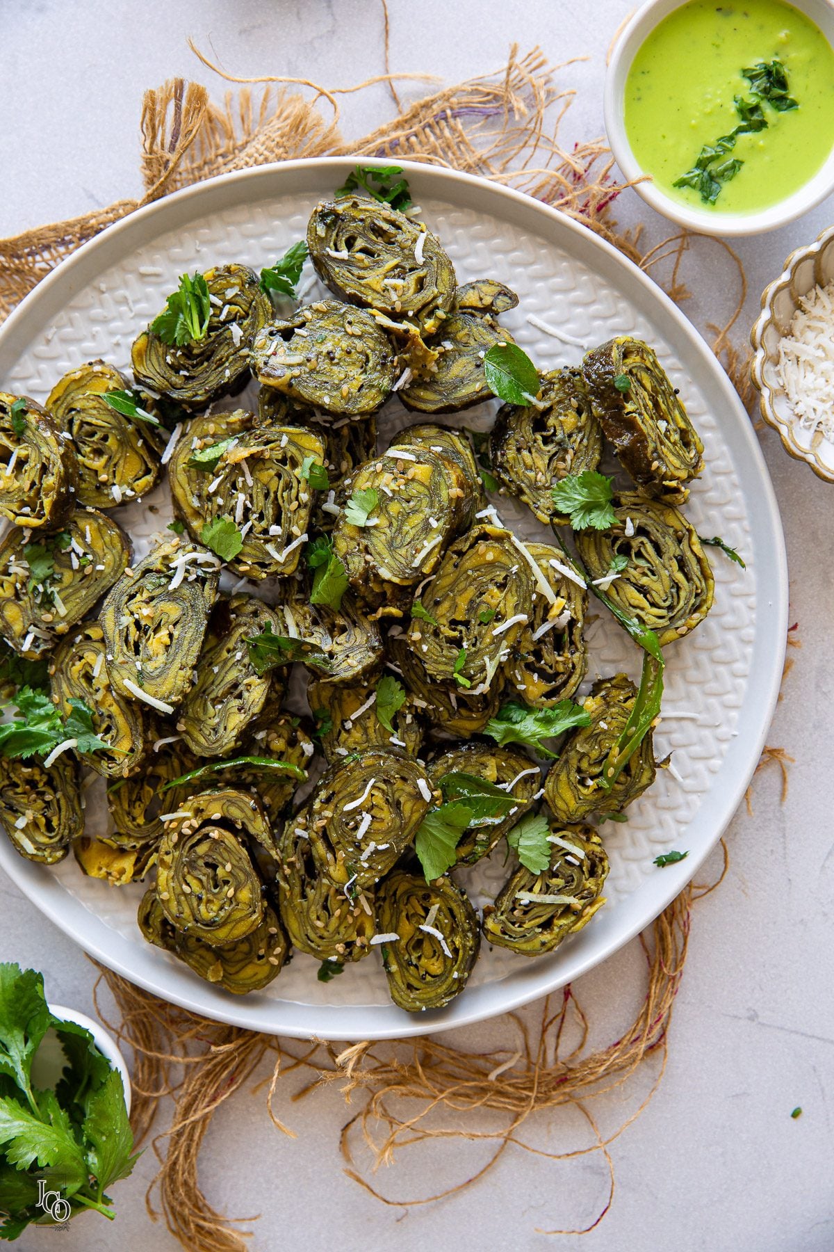 Gujarati farsan patra pieces served on a plate, garnished with chopped coriander and fresh coconut.