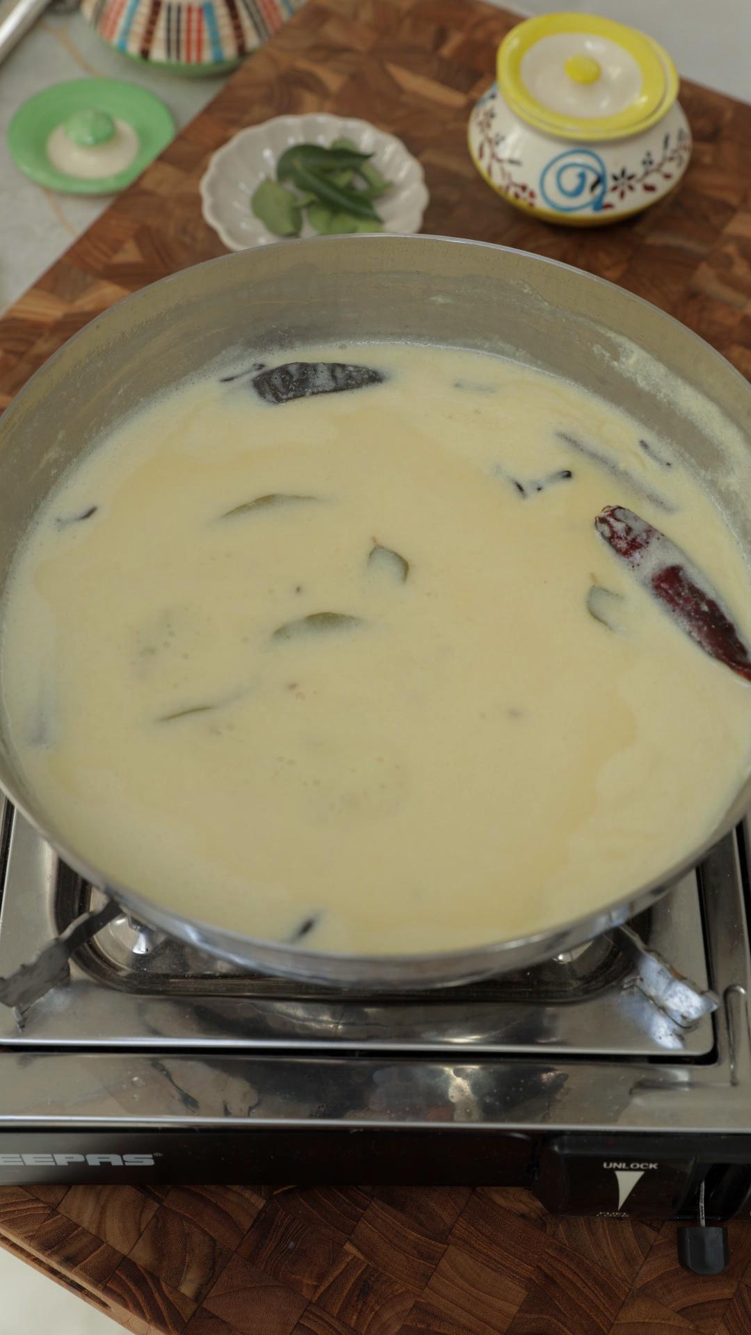 Gently simmering white kadhi in a pan. 