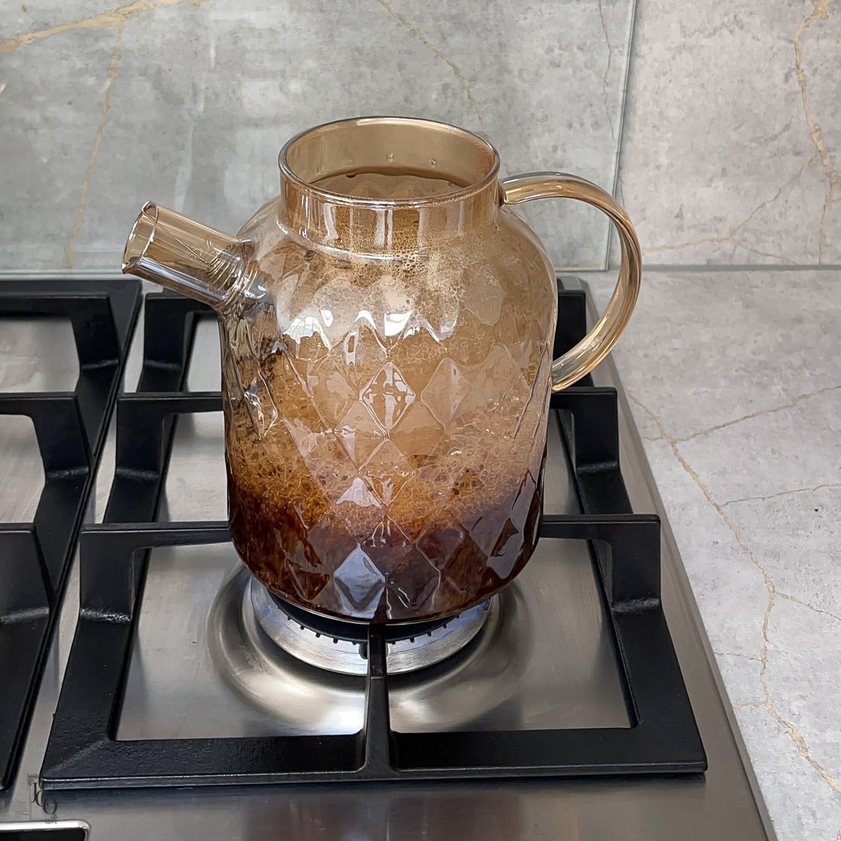 Black tea brewing in a glass kettle.