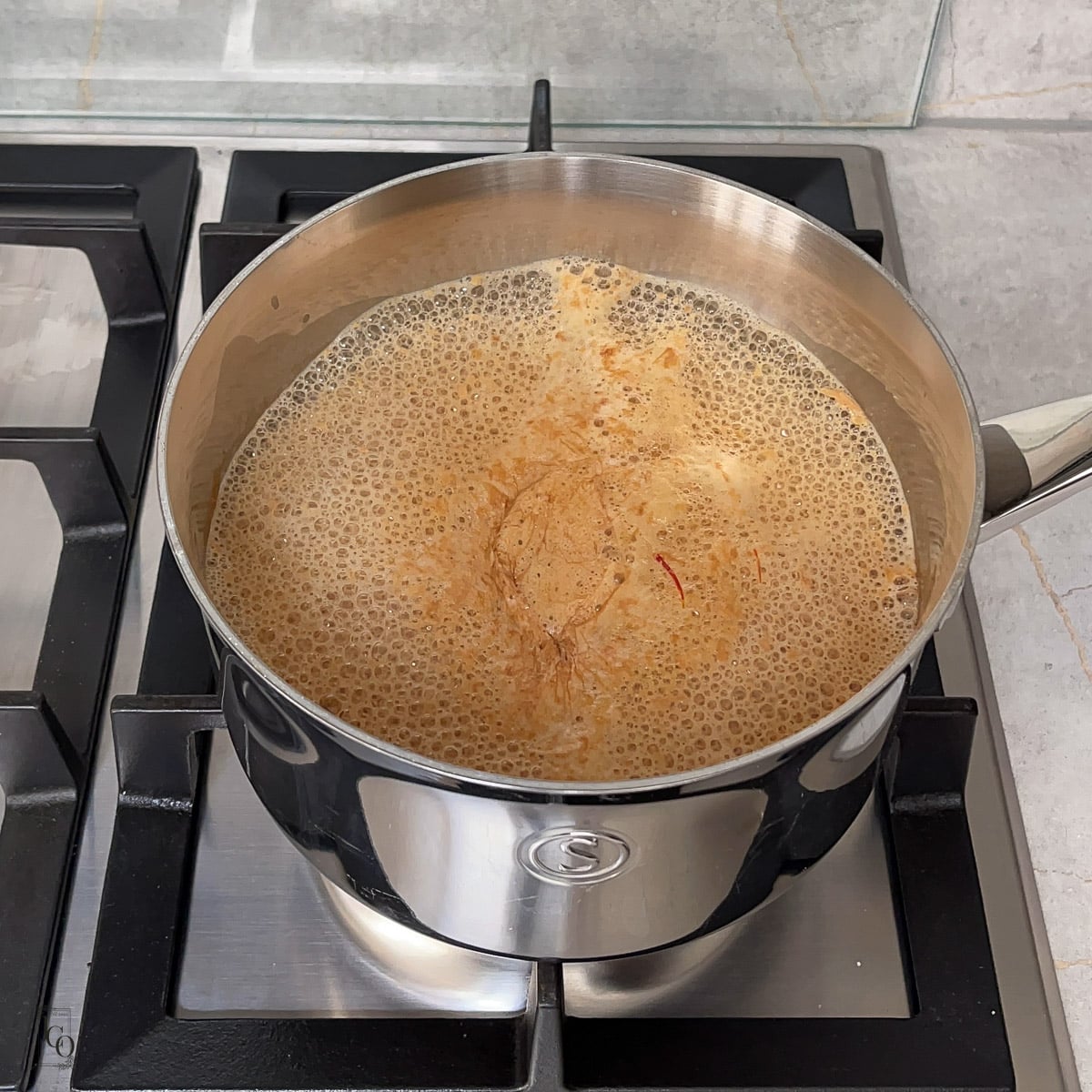 Saffron milk tea simmering in a pan.