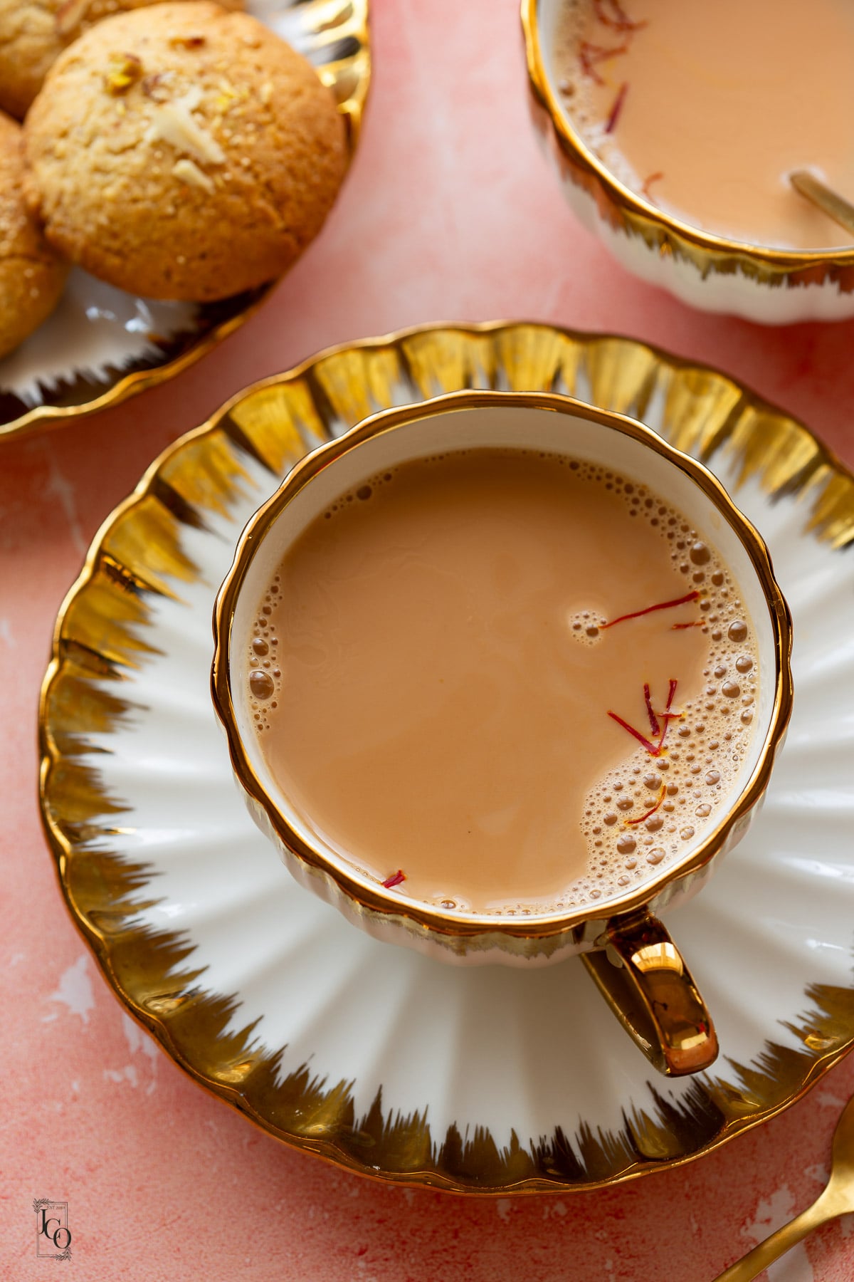 Saffron milk tea served with indian cookies on the side.