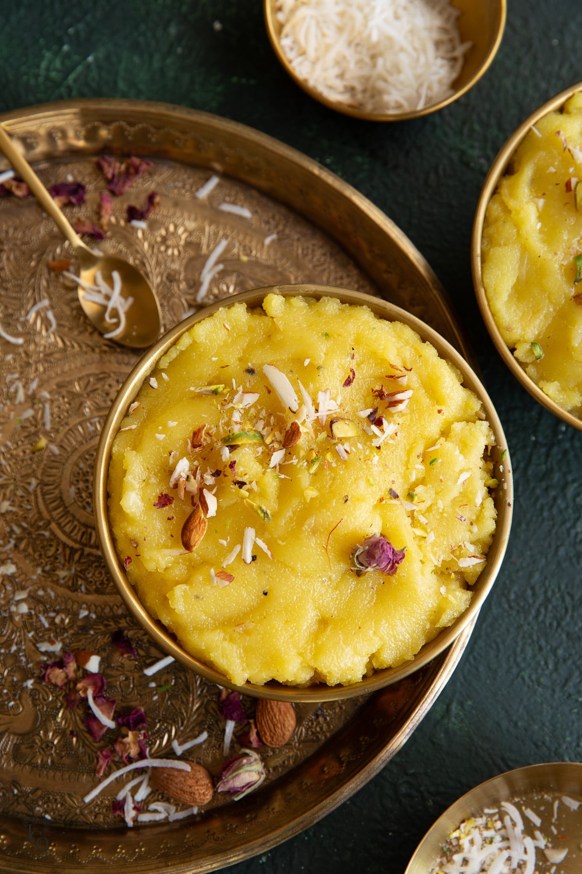 Two metal bowls filled with sooji coconut halwa placed on a tray.