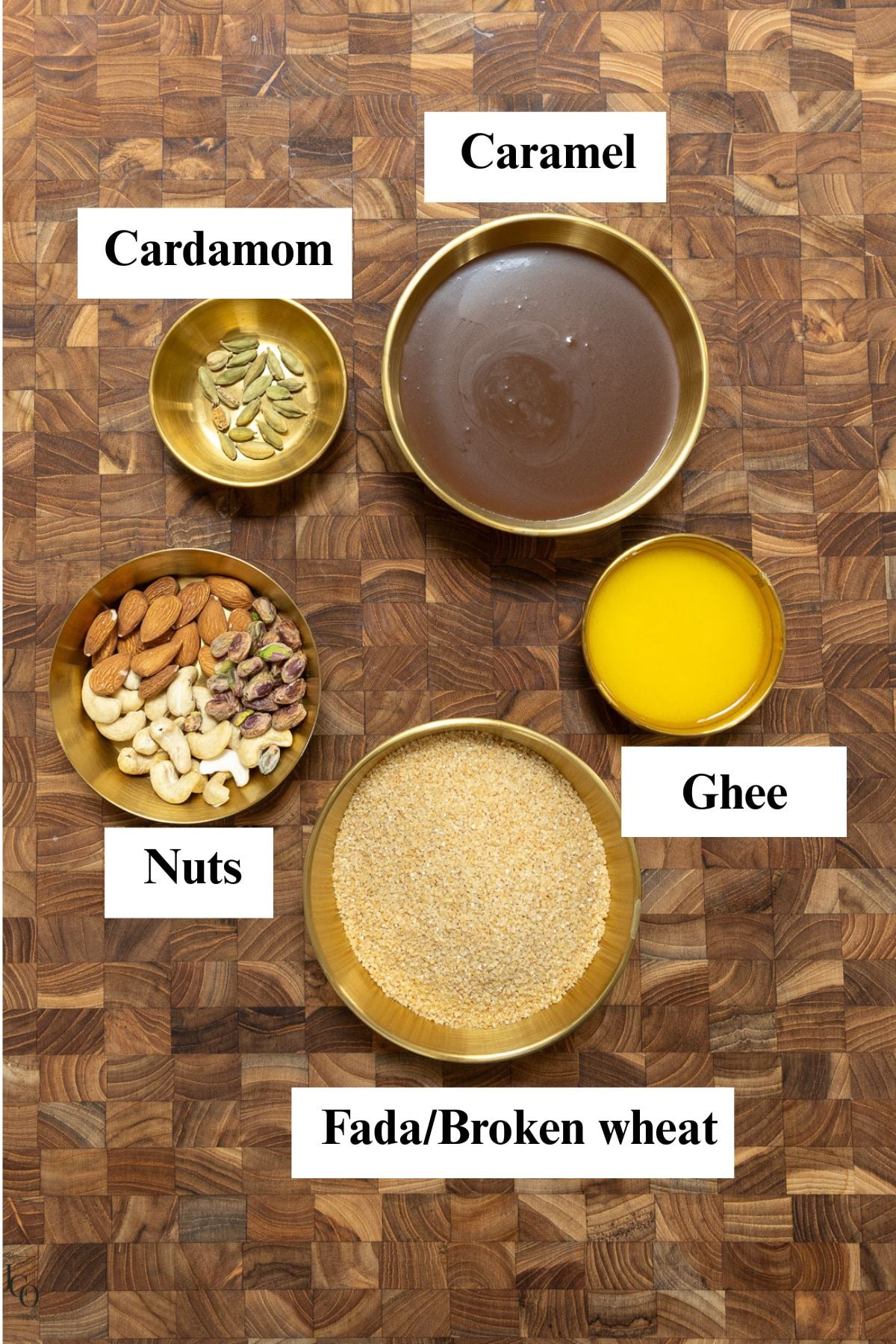 Broken wheat, caramel, ghee, nuts and cardamom in bowls.