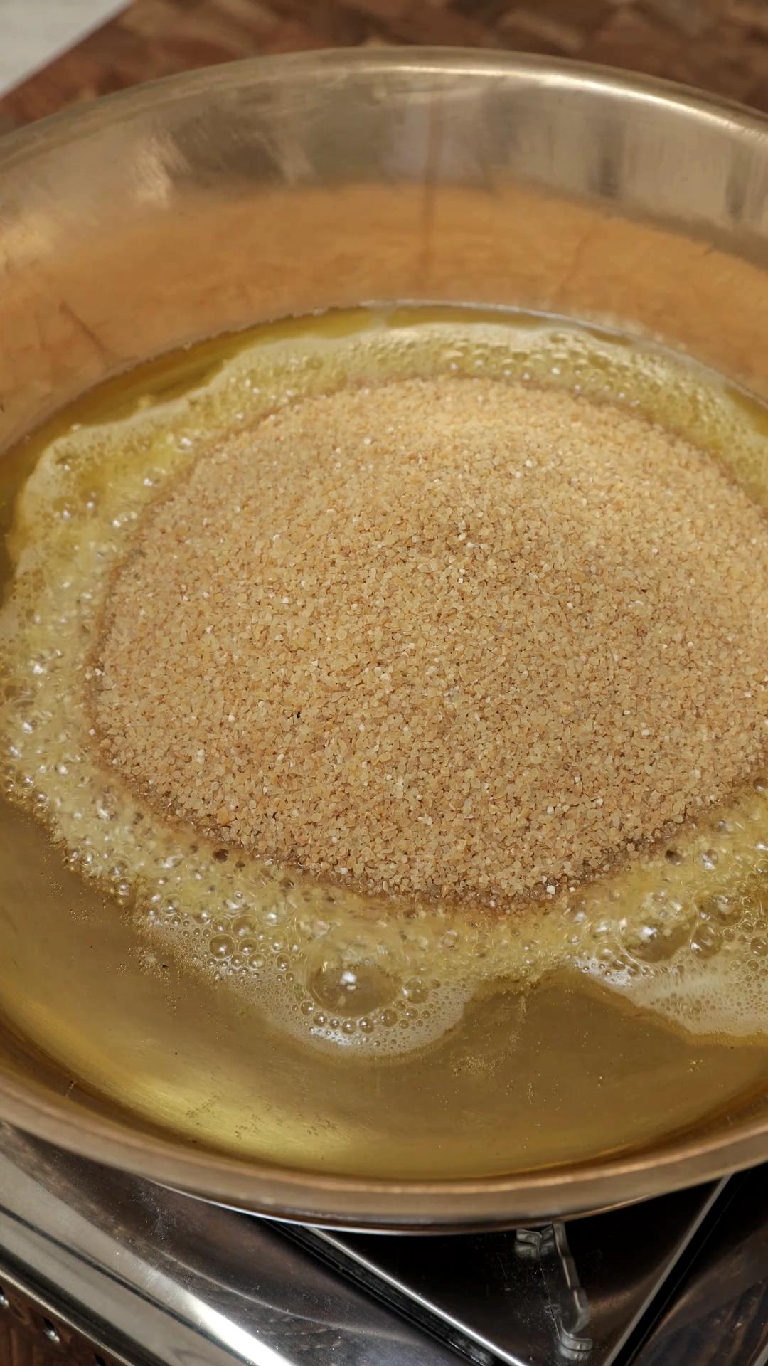 Cracked wheat added to the melted ghee in a pan.