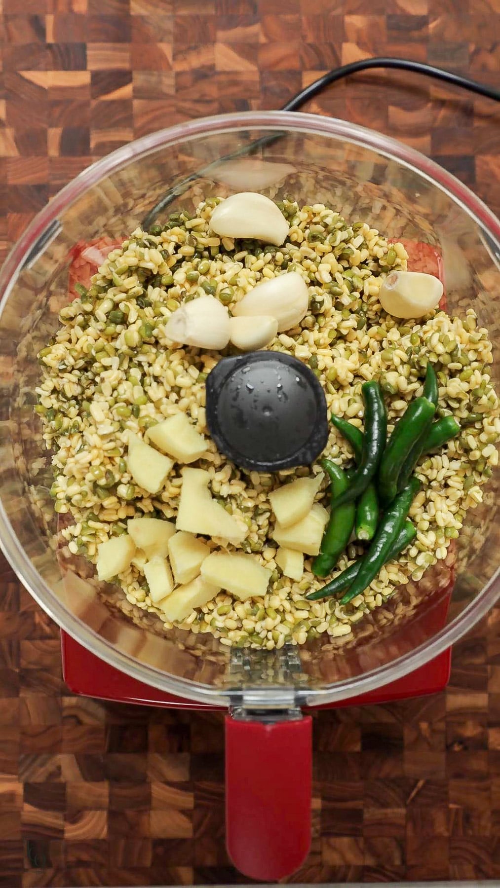 Peeled garlic, ginger and green chillies with drained soaked moong dal in a blender jar. 