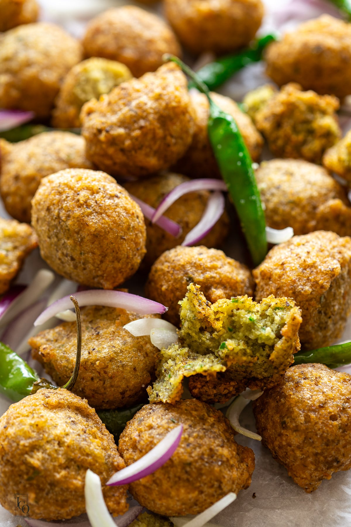 Half piece of moong dal vada with fluffy interior with stack of dal vada. 