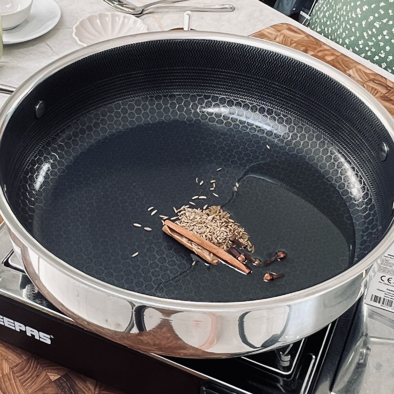 Whole spices added to the hot oil in a pan.