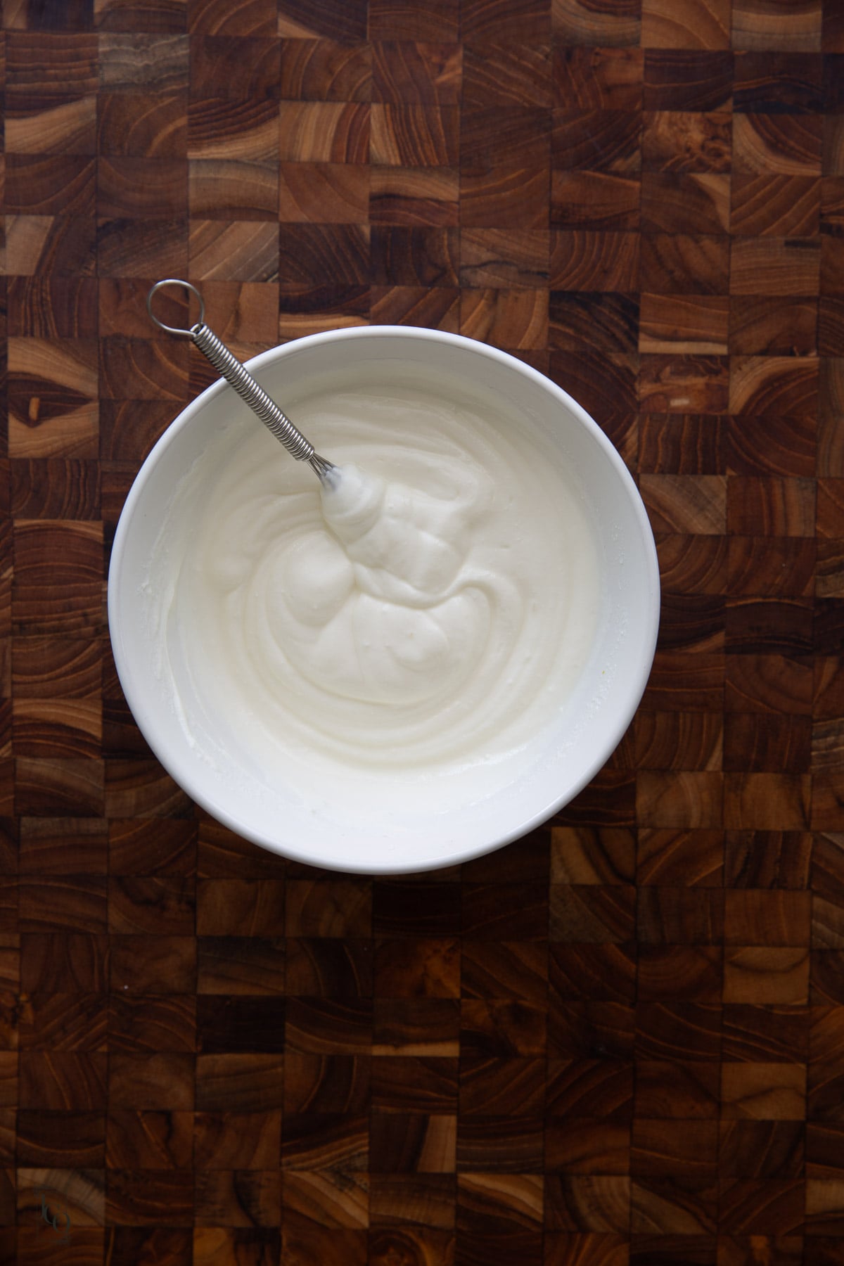 Plain whisked yogurt in a white bowl. 