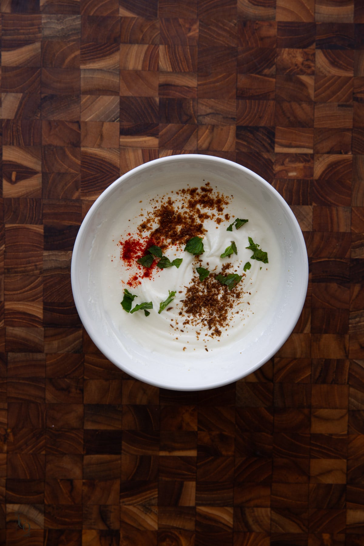 Roasted cumin powder, torn mint and chilli powder added to the whisked plain yogurt.