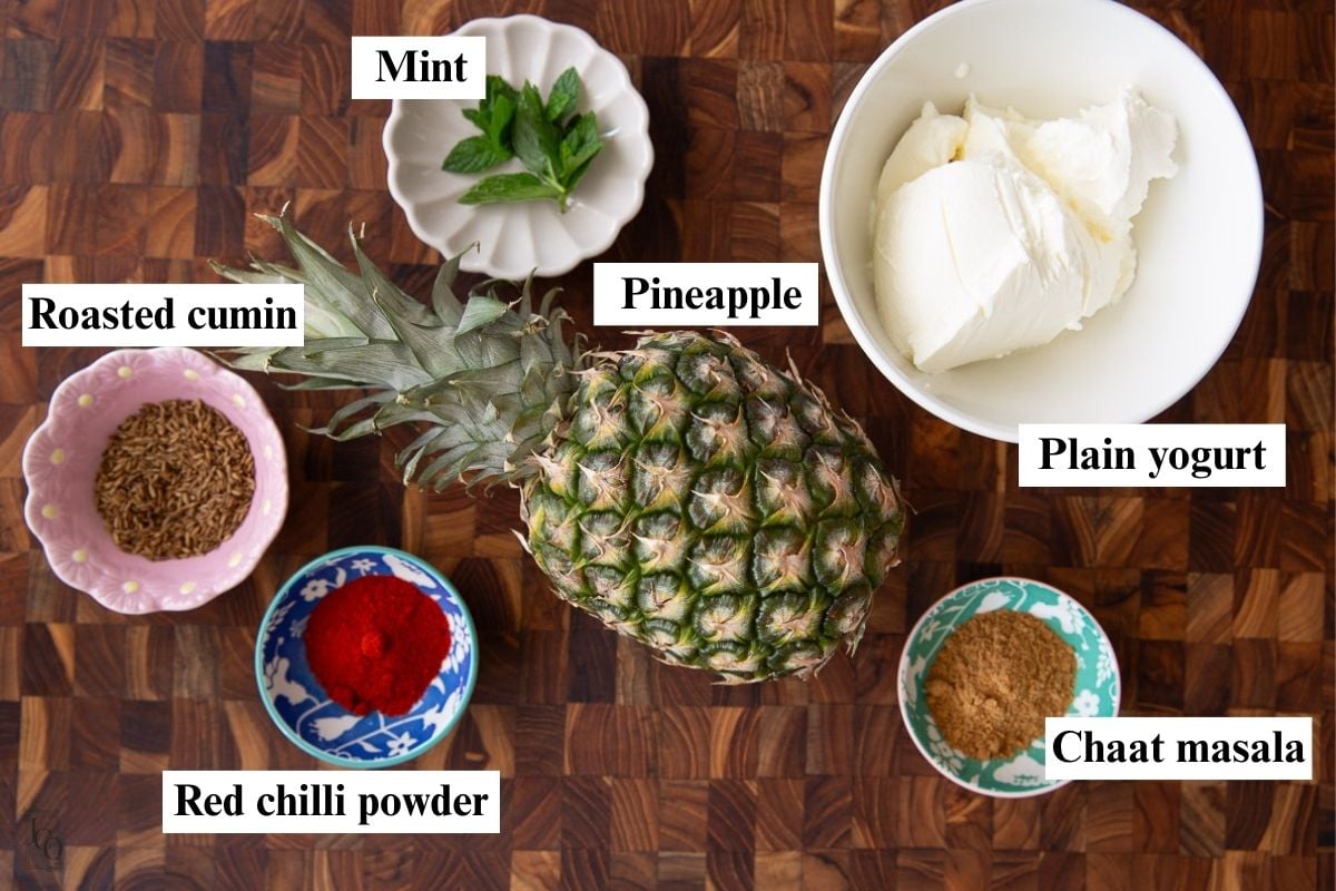 Fresh pineapple, yogurt, spices and mint leaves in bowls. 
