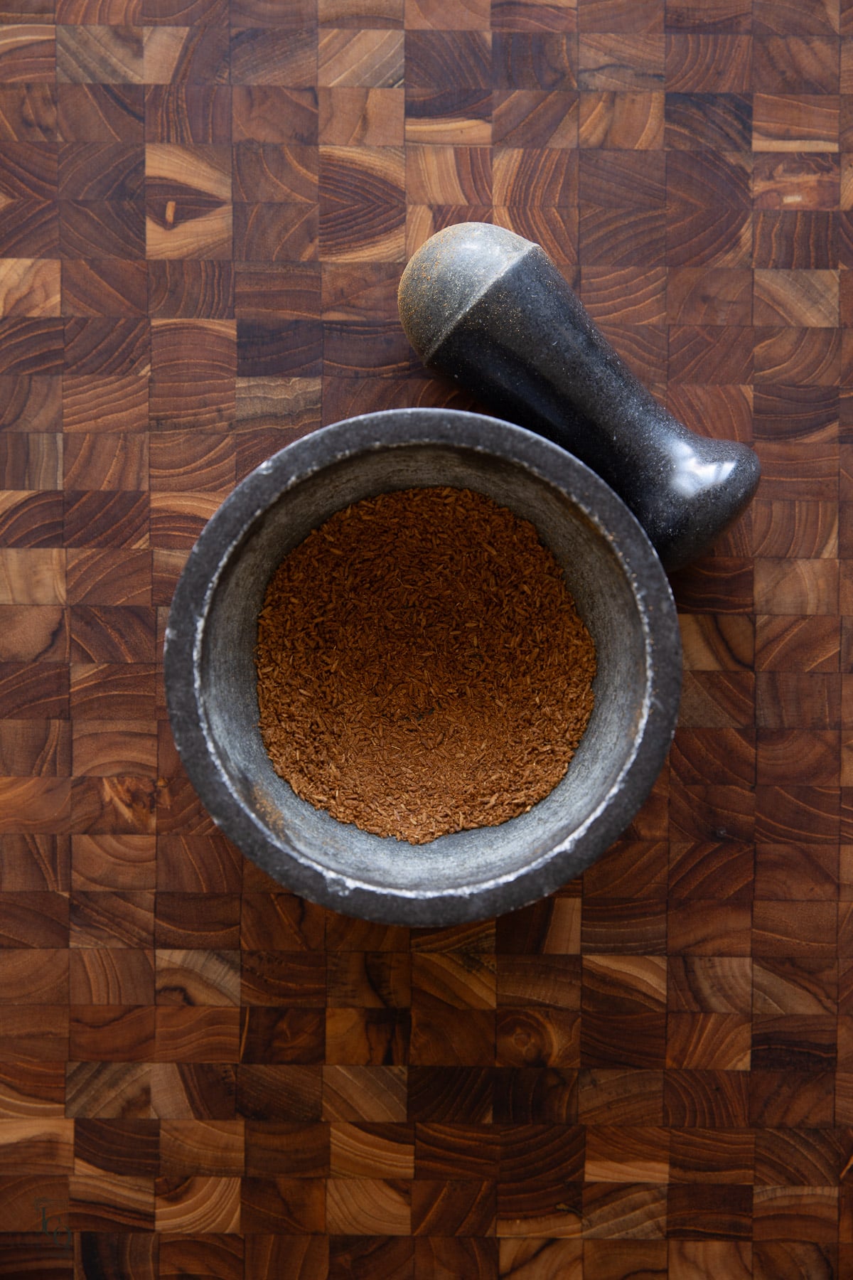 Roasted cumin ground in a pestle and mortar. 