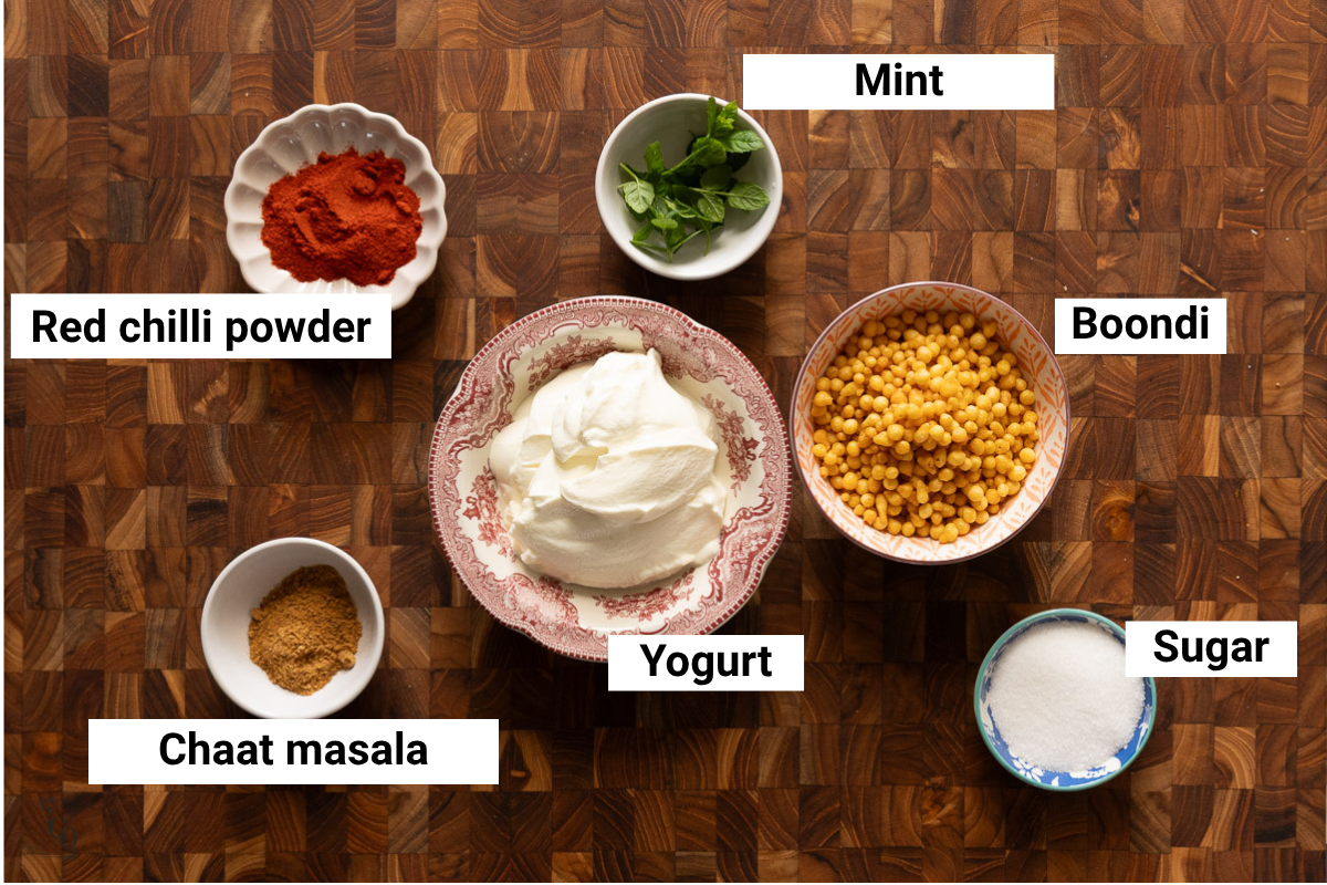 Plain yogurt, boondi. spices, sugar and mint in bowls.