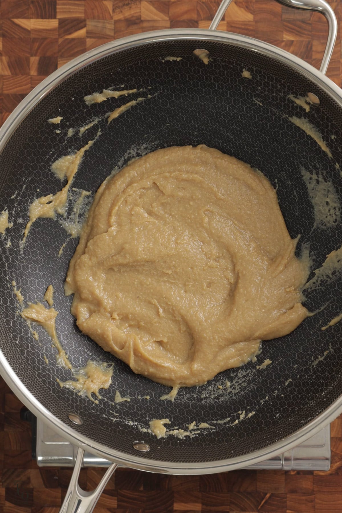 Light brown coloured butterscotch barfi mixture in a pan. 