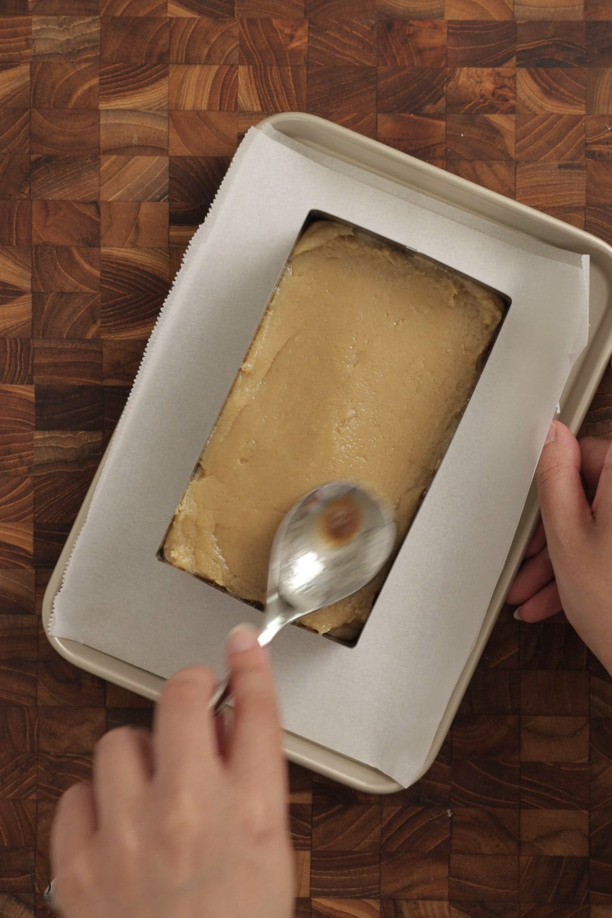 Brown burfi mixture evenly setting in a tray. 