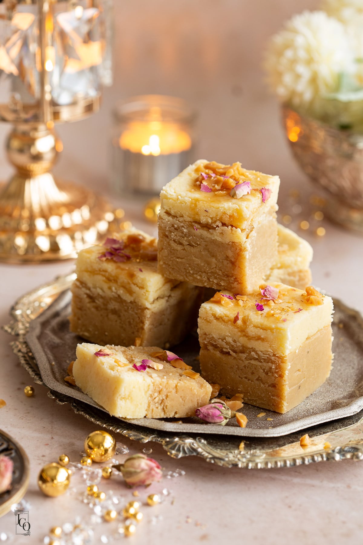 Four and half square butterscotch barfi pieces arranged on a decorative serving tray. 