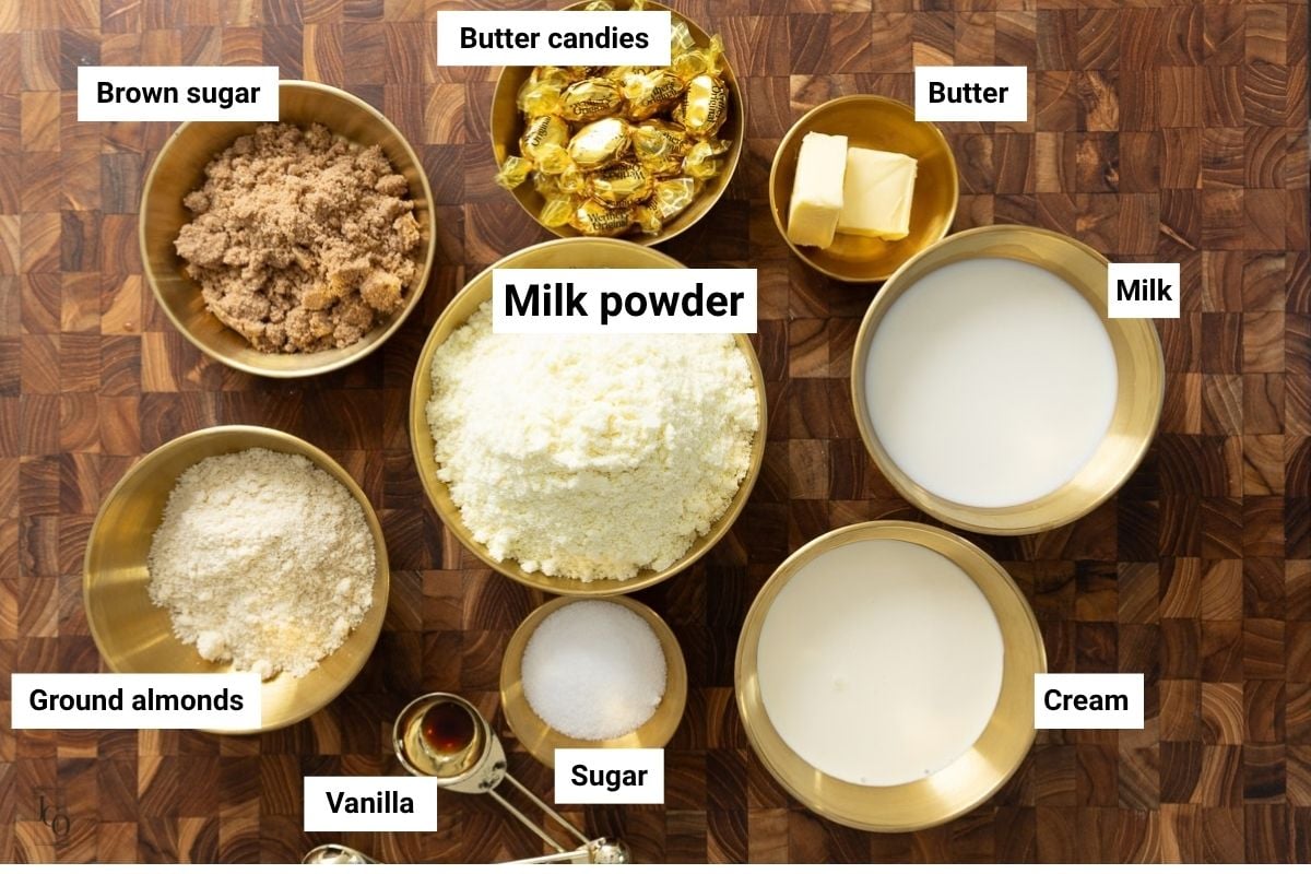 Milk powder, almond powder, milk, cream, sugar and butter in bowls. 