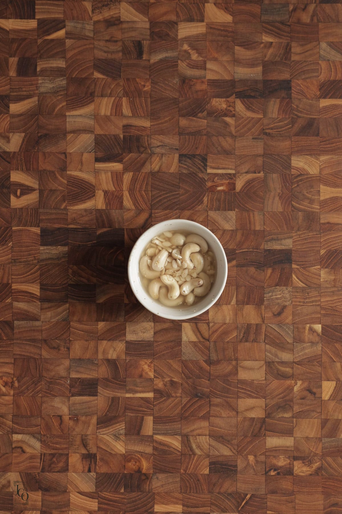 Cashews, white poppy seeds and melon seeds soaking in water in a bowl.