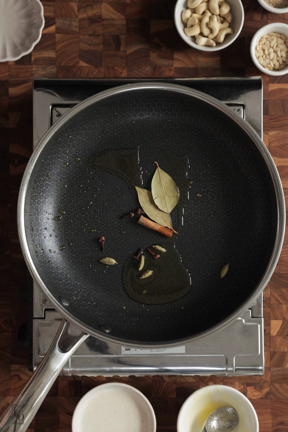 Whole spices blooming in hot ghee in a pan.