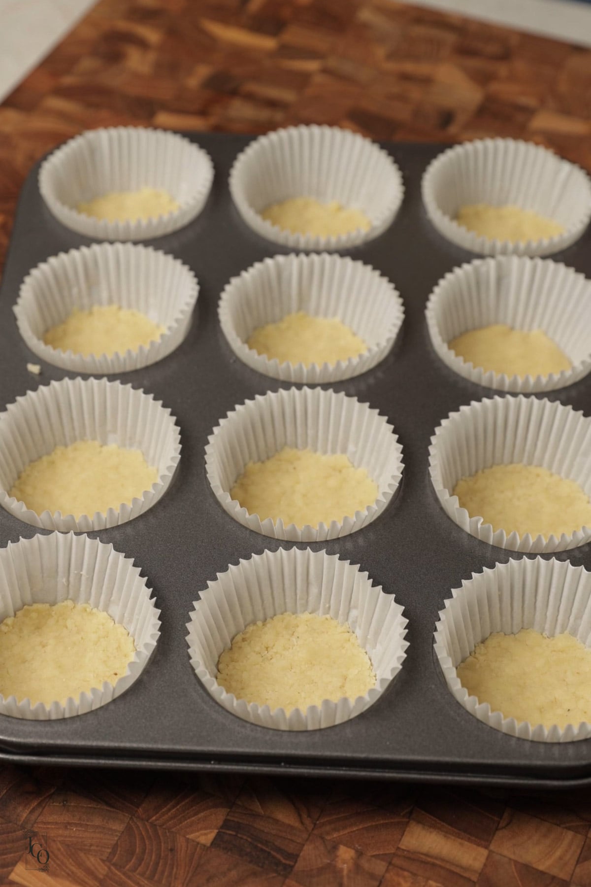 Shortbread dough pressed in muffin cases in a muffin tray.