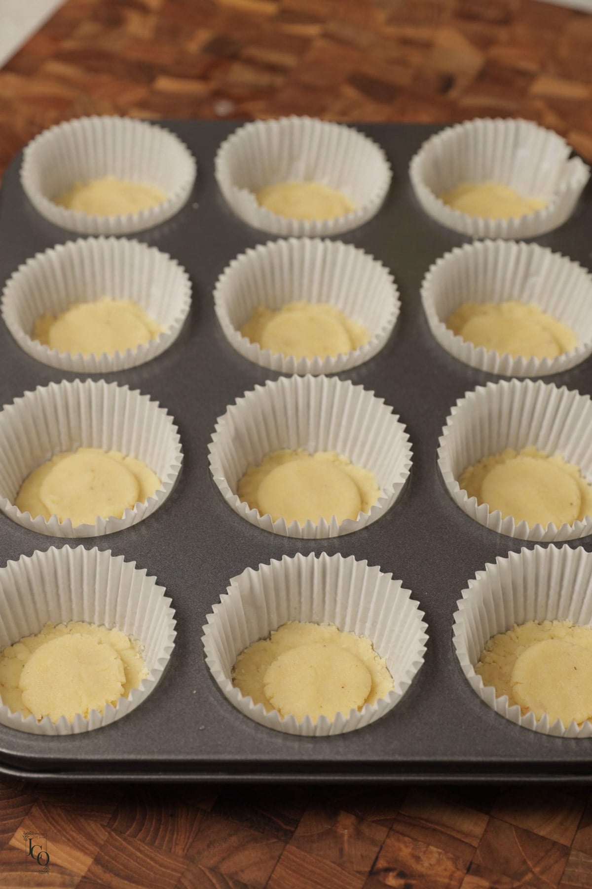Small disc of almond marzipan placed on pressed cookie dough in muffin cases.