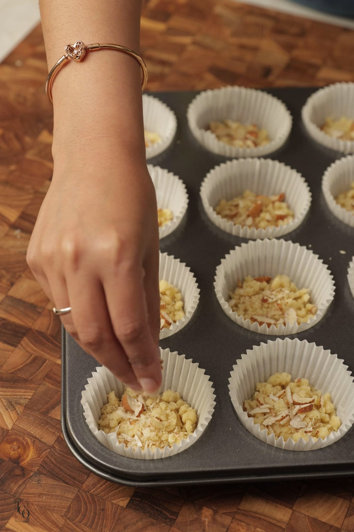 A female hand is sprinkling chopped almonds on cookie dough.