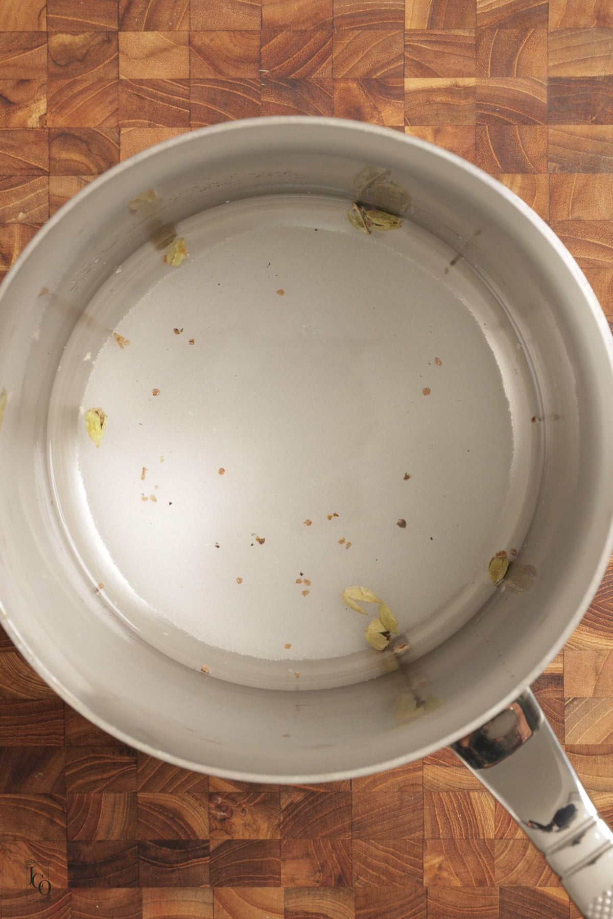 White sugar, water and crushed cardamom pods in a saucepan.