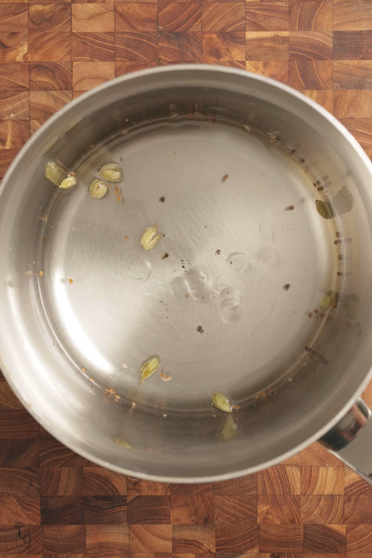 Simple syrup with crushed cardamom pods in a pan.